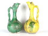 une paire de vases verts et jaunes posés l'un à côté de l'autre sur une surface blanche