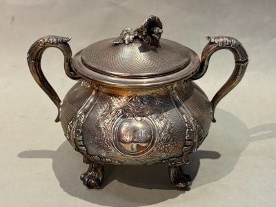 a silver teapot sitting on a table with a lid