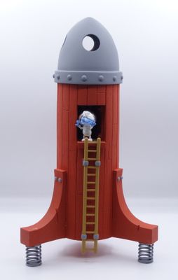une petite fusée jouet avec un bonhomme au sommet