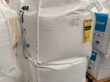 une grande pile de sacs blancs posée sur une palette dans un entrepôt