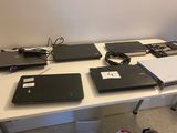 Plusieurs ordinateurs portables sont posés sur une table dans une pièce