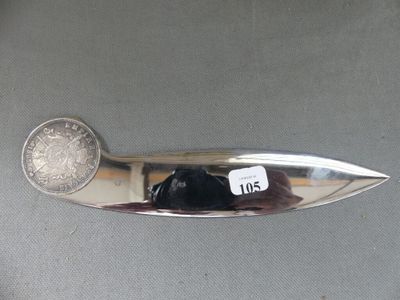 un couteau en argent posé sur une table, à côté d'une pièce de monnaie