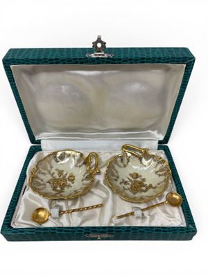 two tea cups and saucers in a box with a spoon and spoon