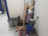 un mannequin dans un coin de la pièce, à côté d'une poubelle