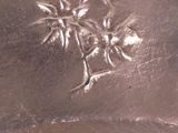 a silver vase with flowers on it sitting on a table