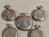 four silver pocket watches are sitting next to each other on a table