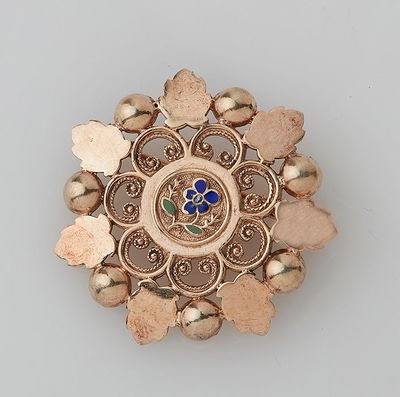 an image of a gold broochle with a blue flower in the center