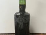 une vieille bouteille noire avec une étiquette verte posée sur une table en bois
