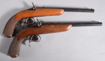 une paire de pistolets à crosse en bois posés sur une surface blanche