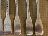 four silver spoons with different designs on them sitting on a table