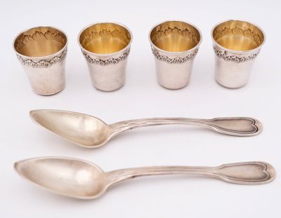 four silver cups and spoons sitting next to each other on a white surface