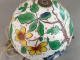 a decorative egg with flowers and leaves painted on it