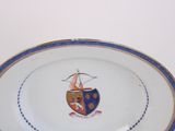 someone is holding a plate with a coat of arms on it