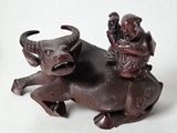 une figurine représentant un homme chevauchant un taureau avec un enfant sur le dos