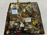 une boîte métallique remplie d'objets divers posée sur une surface blanche