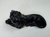 a black statue of a lion laying down on a white surface