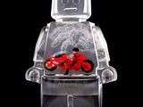 un bonhomme Lego avec une moto rouge dans une vitrine transparente