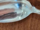 a silver spoon on a wooden table with a spoon in the background