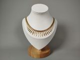 collier posé sur un support en bois, sur fond gris