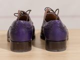 pair of purple shoes on a wooden table with a white wall in the background