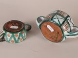 pair of ceramic teapots and saucer with a lid