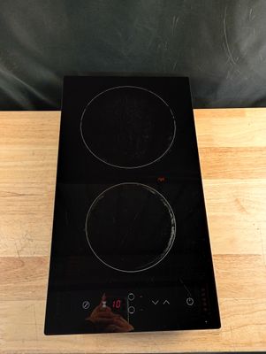 une plaque de cuisson noire à deux feux posée sur une table en bois