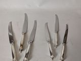 four silver plated knives and a knife holder on a white surface