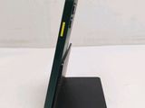 a green cell phone on a black stand on a white surface
