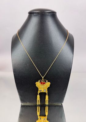 a gold necklace with a red heart on top of a mannequin