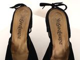 the woman ' s shoes are black sued and have a bow on the toe
