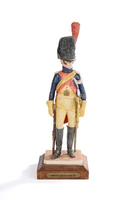 figurine of a soldier with a red hat and uniform on a wooden base