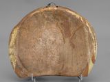 an old wooden bowl with a metal stand on a gray surface