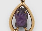 un gros plan sur une pierre violette sertie dans un pendentif plaqué or