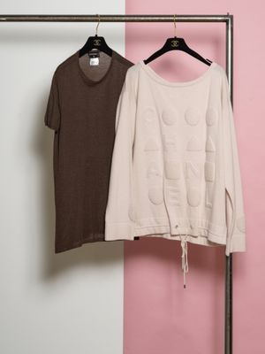 deux chemises suspendues à un portant devant un mur rose et blanc
