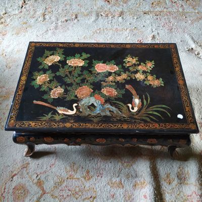 une table noire sur laquelle sont peints des fleurs et des oiseaux