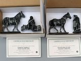 two black figurines of horses and a man in a carriage