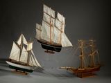 trois maquettes de bateaux exposées sur une table