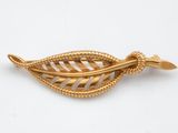 un gros plan d'une broche en feuille d'or sur fond blanc
