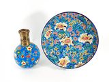 a blue plate and a small vase sitting next to each other