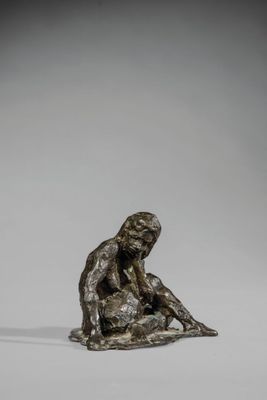 une statue en bronze représentant un homme assis par terre