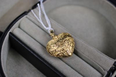 a gold heart shaped pendant sitting in a case