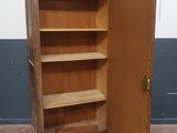 une armoire en bois dont la porte est ouverte, dans une pièce