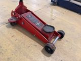 a red jack sitting on the floor in a garage