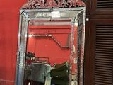 un miroir posé sur le sol devant un mur rouge