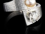 bague en argent ornée d'une perle et d'un diamant sur un fond noir