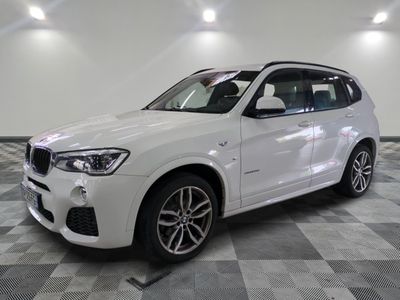 the white bmw suv is parked in a large room