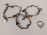 trois bracelets en argent ornés de perles en bois et une bague, posés sur un fond blanc