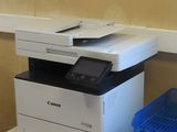 une imprimante posée sur un bureau, à côté d'une pile de magazines