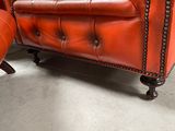 an orange leather chair and ottoman in a room with a white floor