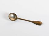 an antique spoon on a white surface with a small spoon sticking out of it